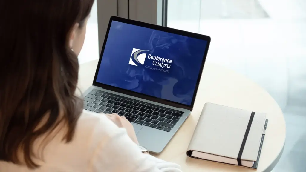 A woman using a laptop displaying the Conference Catalysts Catalyze Platform.