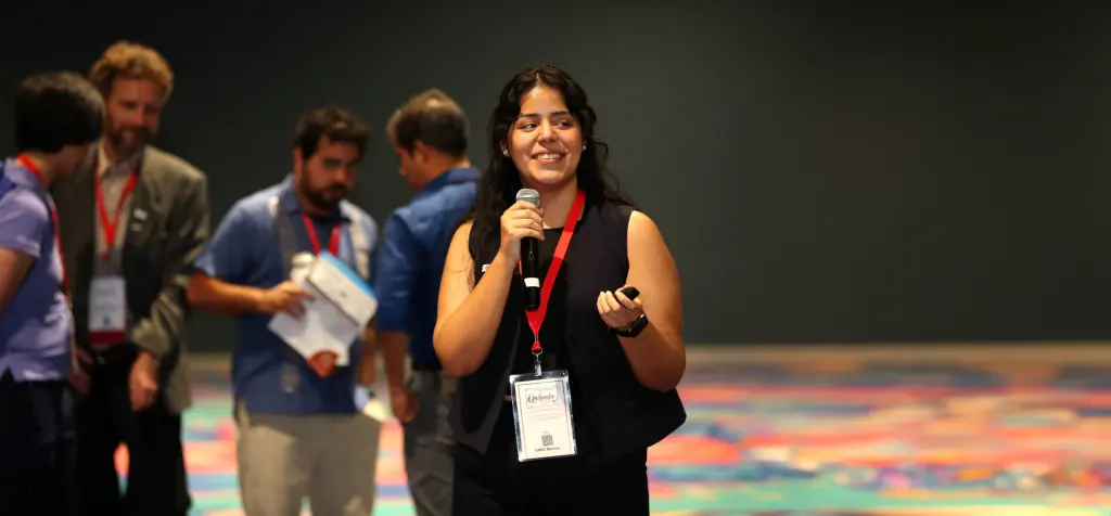 A conference attendee smiling while speaking into a microphone.