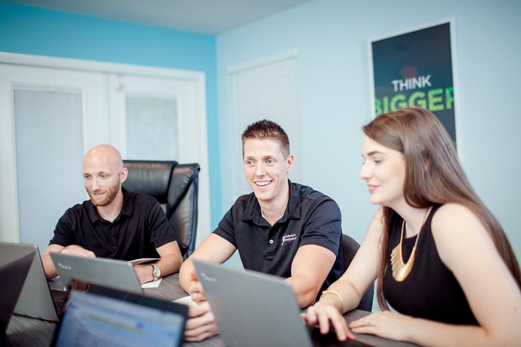 Conference Catalysts staff smiling while working on laptops in a meeting room.