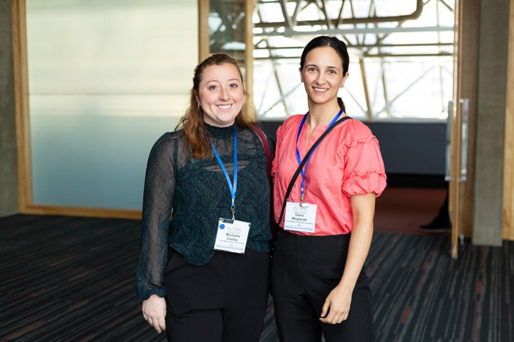 Two smiling attendees posing together in a convention center.