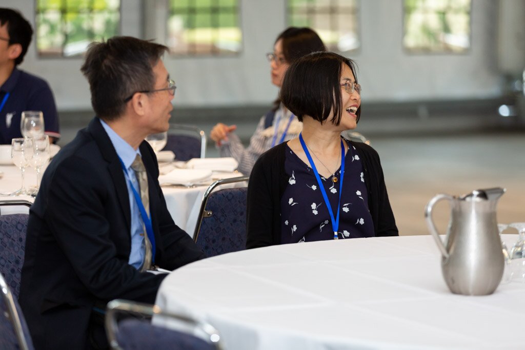 Attendees smiling at a banquet table during a conference meal.