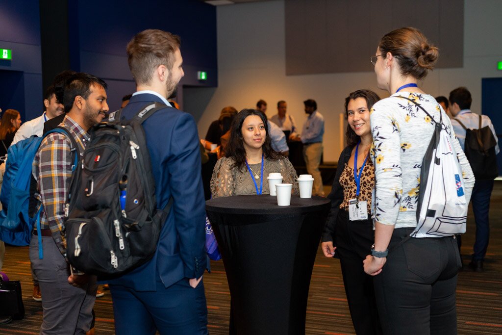 Attendees networking around a cocktail table in a conference reception.