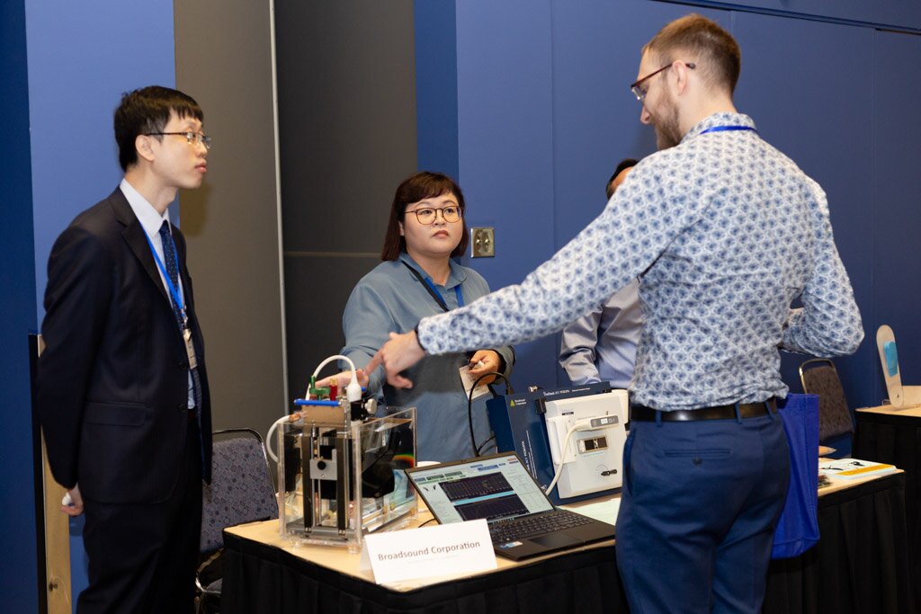An exhibitor demonstrating equipment to attendees at a booth.