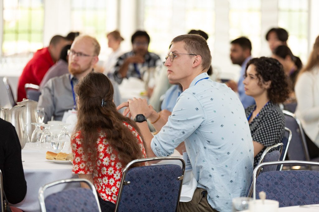 Attendees seated at banquet tables listening to a speaker.