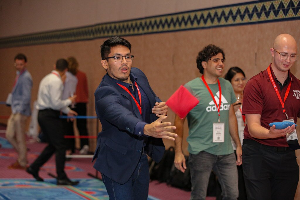 Attendees playing cornhole during a conference social activity.