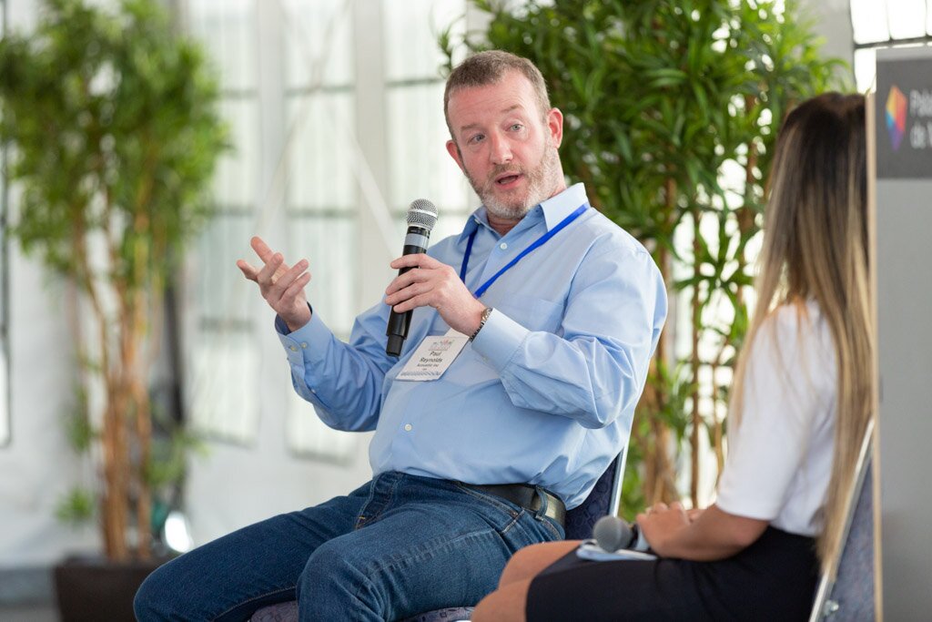 A panelist speaking into a microphone during an on-stage discussion.